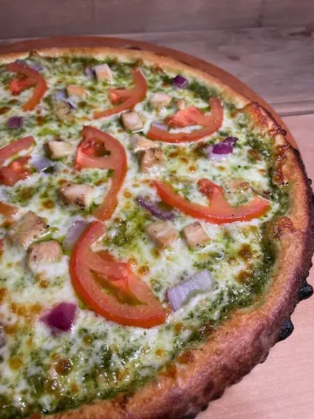 Pesto pizza with chicken and tomato on a wood-fired base