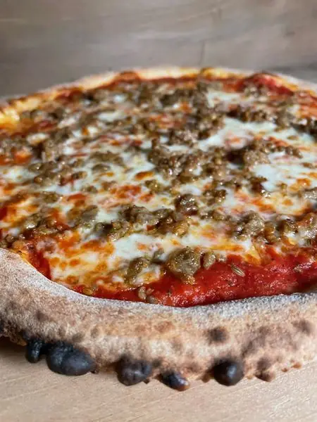 Sausage pizza with a strong wood-fired char on the crust