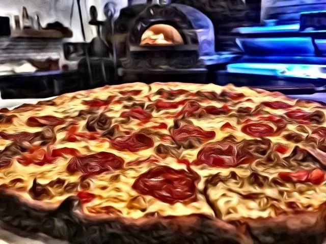 Pepperoni pizza with the wood-fired oven visible behind it