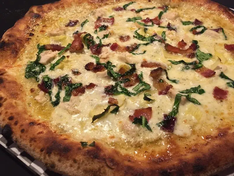 Chicken, bacon, spinach and artichoke pizza on a white sauce base, the Hailey's Comet